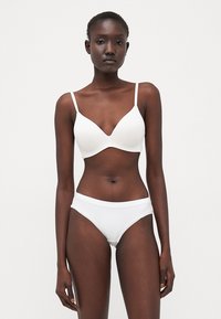 Vitt bh och matchande bikinitrosa, med en slät yta och justerbara band samt en klassisk design i minimalistisk stil.