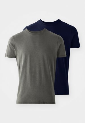 Divi īsām piedurknēm T-krekli: viens olivu zaļš un otrs tumši zils. Abiem ir apaļas kakla izgriezumi un gluda, kokvilnai līdzīga tekstūra.