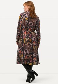Langärmliges, schwarzes Kleid mit bunten Blumenwirbeln, tailliert und mit glatter Textur, bis zu den Knöcheln geschnitten.