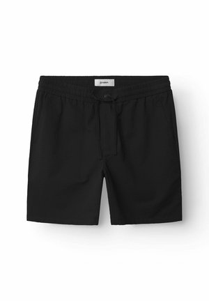 Mustad mustad ujumispüksid elastse vöökohtade ja nööriga sulgemisega, tekstureeritud kangast. Sisaldab küljetaskuid ja on üle põlve pikkusega.