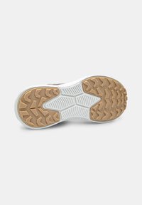 Sole of a sneaker with white and tan tread featuring geometric patterns and textured grip areas on a plain light background.