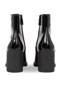 Stivali alla caviglia in pelle patinata nera con punta quadrata, chiusura con zip laterale e tacco a blocco impreziosito con il logo CK. Finitura lucida.