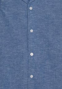 Camicia button-up in lino blu con una finitura testurizzata. Presenta un colletto classico e cinque bottoni bianchi sul davanti.