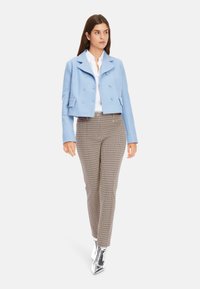 Hellblau cropped, doppelt knopfverschluss Jacke aus strukturiertem Stoff, kombiniert mit karierter Hose und silbernen Ankle Boots.