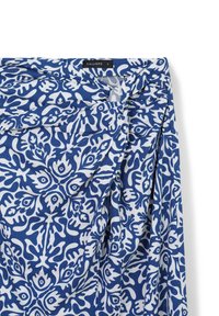Tessuto blu e bianco con un design floreale. Il materiale ha una consistenza morbida. Presenta delle pieghe e un'etichetta con il nome del marchio "CALLIOPE."