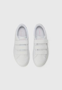 Bijela tenisica s tri čičak trake, glatki sintetički materijal, okrugli vrh, podstava s ublaženjem i suptilan detalj s Lacoste logotipom.