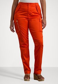 Orange cargo byxor med en slät textur, med sidofickor, en ficka med dragkedja och rak benstil. Parades med klacksandaler.