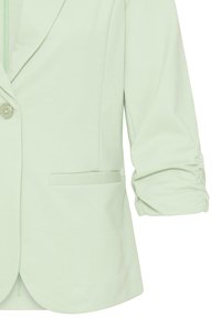 Blazer vert clair avec manches froncées, fermeture à un seul bouton, col cranté et une poche avant horizontale.