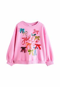 Różowy sweatshirt z okrągłym dekoltem i bufiastymi rękawami. Zawiera kolorowe aplikacje w kształcie kokard oraz słowo "jolly" napisane kursywą.