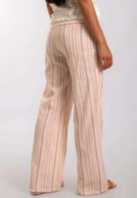 Pantalones de pierna ancha en lino ligero, con rayas verticales en melocotón y blanco, cinturilla elástica y un ajuste relajado.