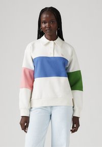 Kremkrāsas polo stila džemperis ar platām horizontālām svītrām zila, rozā un zaļā krāsā. Mīksta audums, ribota aproces un trīs pogu apkakle.