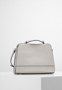 Harmaa teksturoitu nahkalaukku, jossa on rakenteellinen muoto, yläkahva ja säädettävä olkahihna. Varustettu mustilla ompeleilla ja yksityiskohdilla.