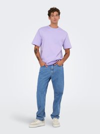 Hele lilla puuvillane t-särk lühikeste varrukatega, millele on sobitatud vabalt istuvad sinised teksad ja valged tossud, omades mugavat disaini.