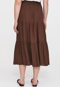 Brąskowa, warstwowa spódnica maxi z lekkiego, gładkiego materiału z elastycznym pasem. Wyraźne, zwiewne warstwy tworzą swobodny styl.