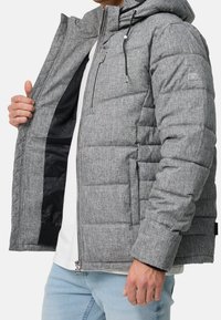 Graue Steppdaunenjacke mit Kapuze, mit gesteppter Textur, Reißverschluss vorne und elastischen Bündchen. Innen schwarz gefüttert mit einer versteckten Tasche.