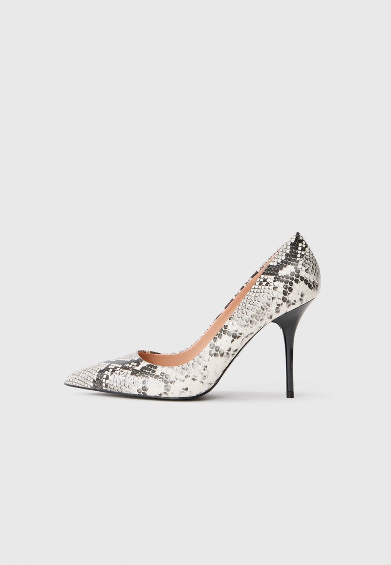 Pointe-blede visoke pete v črno-belem vzorcu kače. Ima elegantno obliko, sijočo površino in tanko stilkasto peto.