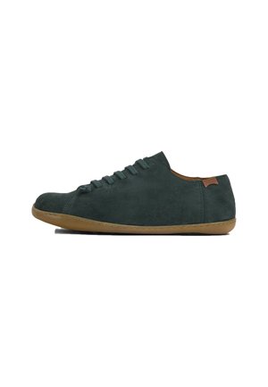 Green suede sneaker with rounded toe, six lace eyelets, tan leather accent at heel, and flexible rubber sole. Minimalist design.