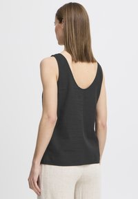 Černý bezrukávový top s hlubokým, zaobleným výstřihem na zádech a jemnou texturou. Materiál má hladký povrch a uvolněný design.