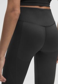 Zwarte high-waisted leggings met ribbeltextuur aan de tailleband en zijkanten, met een gladde afwerking en een aangesloten ontwerp.