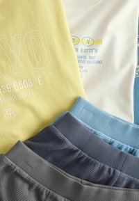 Samling af bomulds-T-shirts i gul, hvid, lyseblå, mørkeblå og grå; med forskellige trykte motiver og teksturerede ribstrikkede kanter.