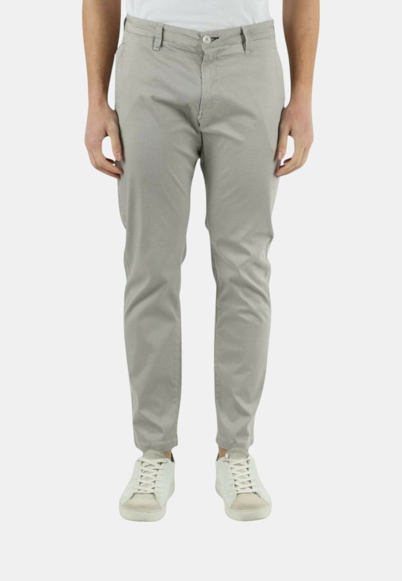 Pantaloni grigio chiaro realizzati in un mix di cotone, con un design slim fit, tasche frontali e chiusura con bottone. Indossati con sneakers bianche.