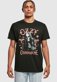 Fekete pamut póló, grafikus nyomattal, melyen napszemüveges figura, pálmafák és denevérek láthatók. A szöveg "Ozzy Osbourne" pink színben olvasható.