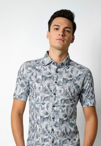 Kurzärmliges Hemd in Hellgrau mit floralem Muster in Grüntönen und Blau. Mit einem Button-Down-Kragen und schwarzen Knöpfen.