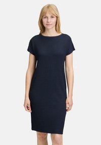 Robe bleu marine à manches courtes avec un motif texturé, silhouette droite et encolure ronde. Le tissu semble respirant et flexible.