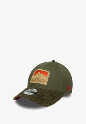 Green baseball cap with a textured brown bill. Features a patch with mountains in red and tan. Constructed from durable fabric.