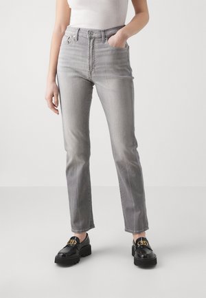 Grijze high-waisted jeans met een straight leg ontwerp, met vijf zakken en subtiele vervaging. Gedragen met zwarte platform loafers.