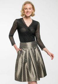 Schwarzes Spitzenoberteil mit langen Ärmeln und V-Ausschnitt, kombiniert mit einem knielangen, metallischen Rock mit einem gemusterten Design und seitlichen Taschen.