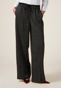 Wijdvallende, donkergrijze broek van een gestructureerde stof met een elastische tailleband. Voorzien van een trekkoordsluiting en zijzakken.