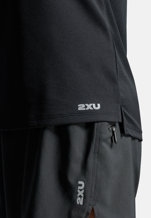 Sort atletisk trøje med struktureret stof; har en lille hvid "2XU" logo ved kanten. Kombineret med sorte shorts, også med "2XU" branding.