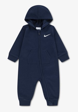 Tmavomodrý detský overal s kapucňou, predným zipsom, klokankovým vreckom, rebrovanými lemami a bielym logom Nike swoosh na hrudi.