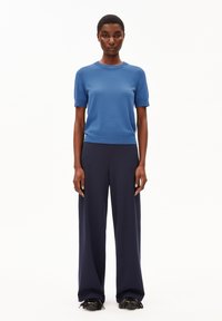 Blå kortärmad stickad tröja tillsammans med högmidjade navy vida byxor och svarta fransade klackskor. Enkla, rena linjer.