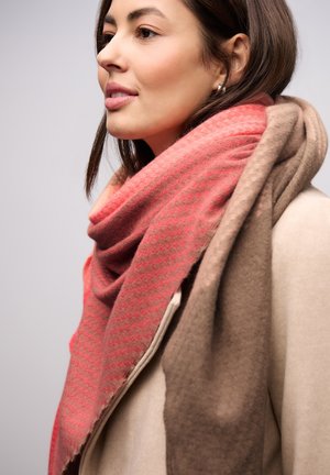 Une écharpe à motifs rouges et bruns en tissu doux, drapée autour du cou, avec un design texturé et des plis légers.