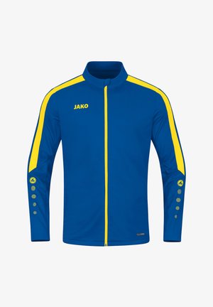 Giacca sportiva blu con colletto alto, accenti gialli lungo le maniche e la zip, e un logo sul petto; presenta bottoni a scatto sulle maniche.