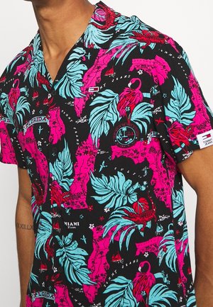 Zwart shirt met korte mouwen, voorzien van een felroze kaart van Florida, turquoise bladeren, rode flamingo's, kleine bootjes en Tommy Jeans-logo's.