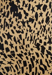 Tessuto beige con una superficie texture caratterizzato da un motivo nero di forme astratte e stelle, creando un design audace e contrastante.