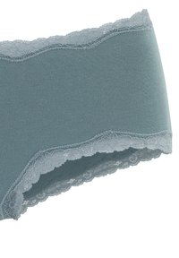 Slip di cotone azzurro chiaro con bordo in pizzo a scallop in vita e aperture delle gambe. Texture liscia con vita elastica.