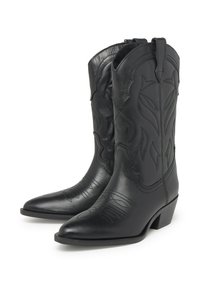 Botas de vaquero de cuero negro con puntas afiladas, costura decorativa y grabado floral. Presentan un tacón bajo y apilado y lengüetas para facilitar la colocación.