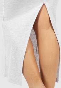Jupe côtelée gris clair avec des fentes latérales, exposant la jambe. Le tissu semble doux avec une finition texturée, présentant des bords propres et droits.