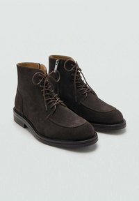 Botas de tobillo de ante marrón oscuro con punta redondeada, cordones en la parte delantera y un ribete de cuero suave, que cuentan con un tacón bajo apilado y costuras detalladas.