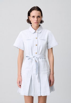 Robe chemise en denim bleu clair avec des manches courtes, un devant boutonné, une ceinture attachée et deux poches avant. Présente un détail de jupe plissée.