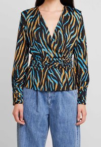 Blusa nera a maniche lunghe con avvolgente caratterizzata da una stampa di zebre colorata in blu e oro, con vita aderente e tessuto testurizzato.