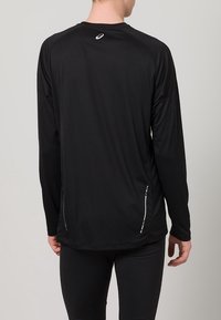 Svart långärmad träningsskjorta med rund hals, flatlock- sömmar och reflexdetaljer på sidorna och ryggen. Tillverkad av ett lättviktsmaterial.