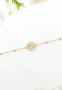Bracciale d'oro con un design a forma di albero circolare caratterizzato da incisioni intricate, accentuato da piccole perline rotonde su una sottile catena.