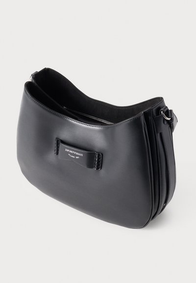 Borsa a spalla in pelle nera con una texture liscia, forma curva, chiusura con zip e un'etichetta con il marchio sulla parte anteriore.