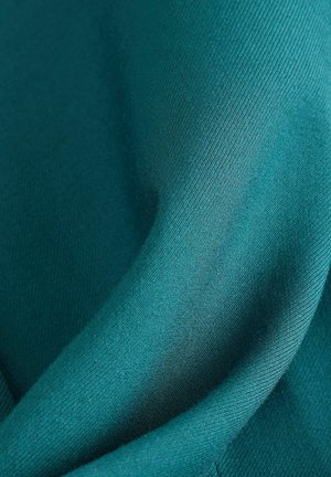 Tyrkysová látka hladkého povrchu s jemným leskem, elegantně se skládá do měkkých záhybů. Má jemný tkaný vzor.