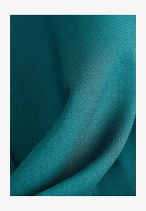 Teal fabric with a smooth texture, displaying a subtle sheen, drapes elegantly in soft folds. Features a fine weave pattern.